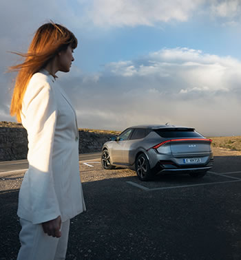 White clad woman in front of a Kia EV6